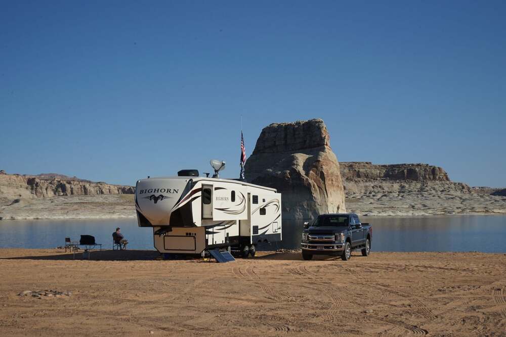 Fifth wheel RV beside a lake and campsite